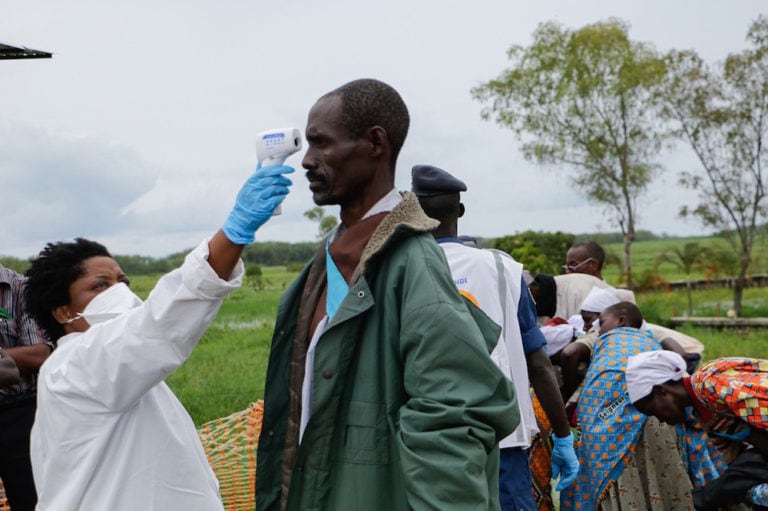 A medical staff member measures a man's temperature as a preventive measure against Covid-19 upon his arrival of repatriation in Gatumba, Burundi, on the border with DRCongo, 18 March 2020, ONESPHORE NIBIGIRA/AFP via Getty Images