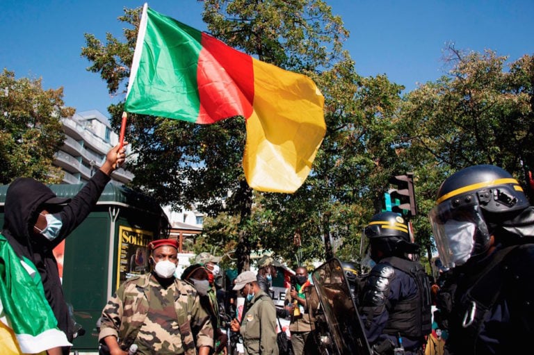 A man waves a Cameroonian national flag in front of French riot policemen during a demonstration against Cameroon's President Paul Biya, near the embassy of Cameroon in Paris, France, 22 September 2020, -/AFP via Getty Images