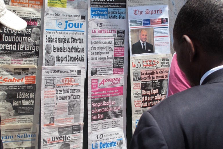 A man looks at the headlines at a newspaper stand in Yaoundé, Cameroon, 26 March 2013, Reinnier KAZE/AFP via Getty Images