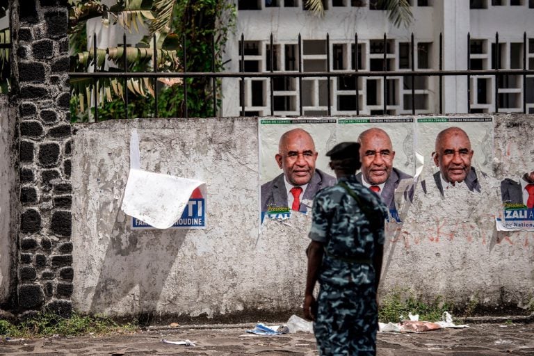 An officer stands in front of campaign posters of incumbent Comoros President and Presidential Candidate Azali Assoumani, in Moroni, 25 March 2019, GIANLUIGI GUERCIA/AFP/Getty Images
