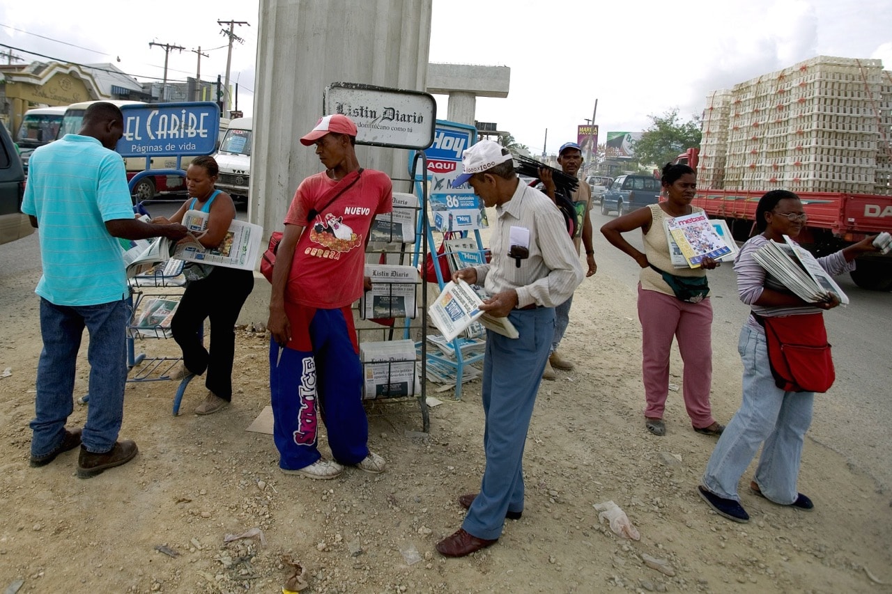 Newspaper and phone card hawkers line the road during morning rush hour in Santo Domingo, Dominican Republic, 3 April 2006, Robert Nickelsberg/Getty Images