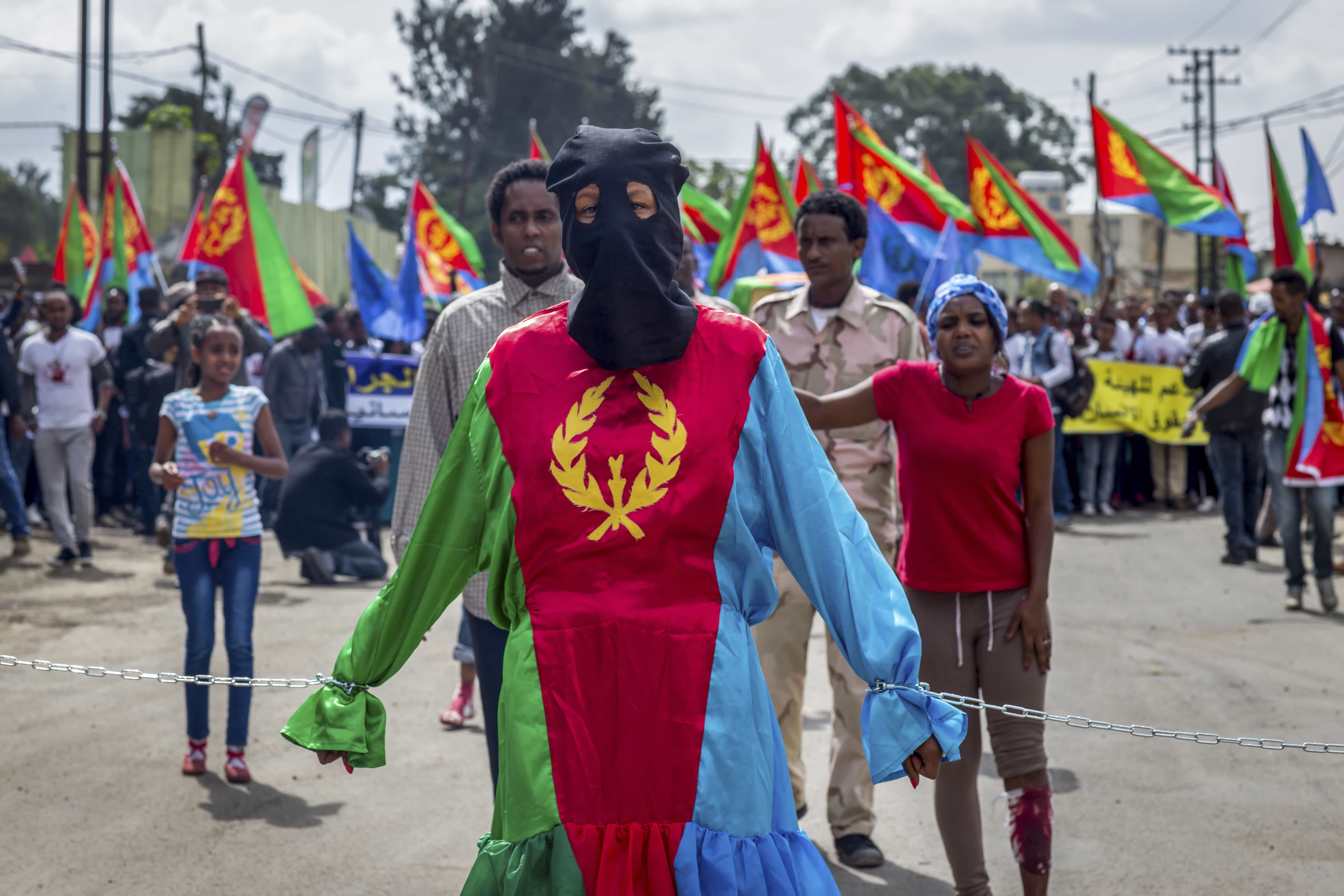 A woman dressed in the colours of the Eritrean flag stands symbolically chained, at a demonstration by Eritrean refugees and dissidents outside the headquarters of the African Union in Addis Ababa, Ethiopia, 23 June 2016, AP Photo/Mulugeta Ayene