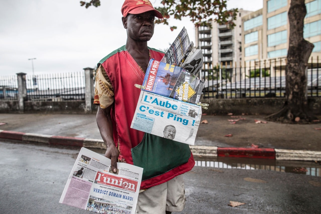 A newspaper vendor looks for customers at a street light in Libreville, Gabon, 29 August 2016, MARCO LONGARI/AFP/Getty Images