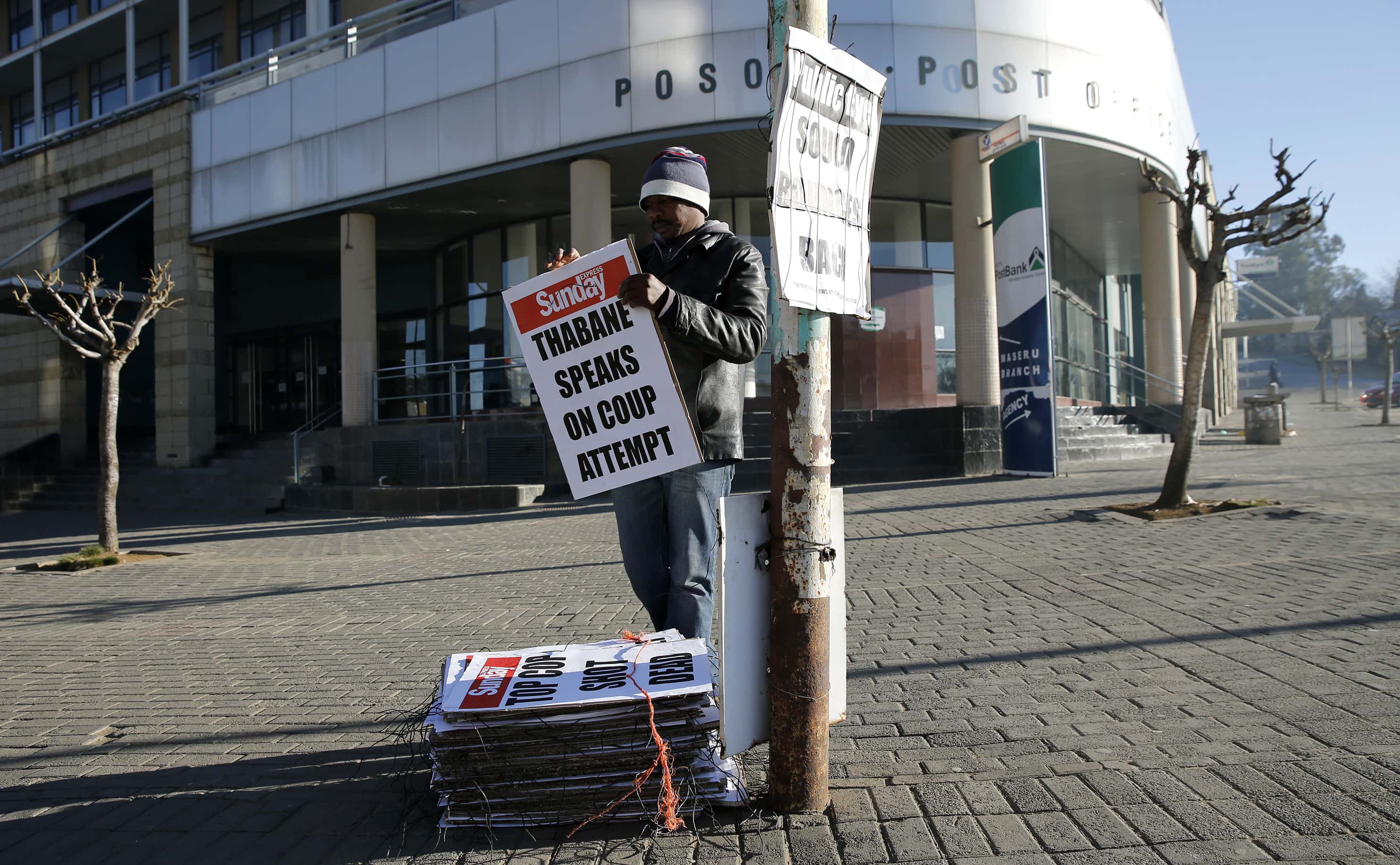 A worker hangs posters displaying newspaper headlines, in Maseru, Lesotho, 31 August 2014, REUTERS/Siphiwe Sibeko