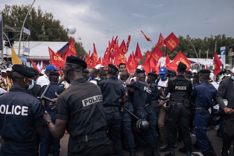 Police officers stop supporters of President Denis Sassou Nguesso from following his vehicle, at the end of his last presidential election campaign rally, in Brazzaville, Republic of Congo, 19 March 2021, ALEXIS HUGUET/AFP via Getty Images