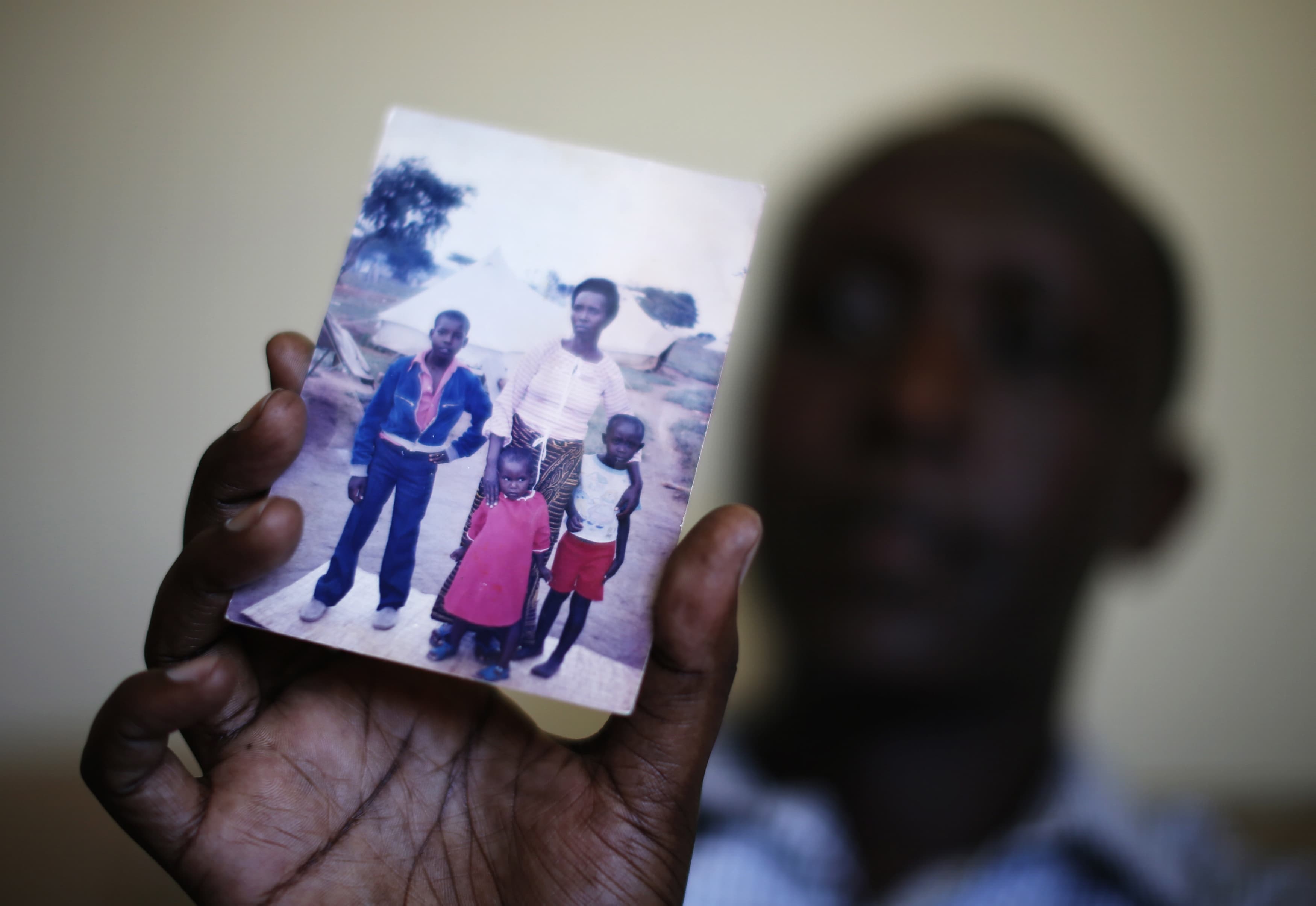 Patrick Manyika holds up a photo of himself and his family. Manyika was born in a Ugandan refugee camp after his Tutsi family fled Rwanda., REUTERS/Lucy Nicholson