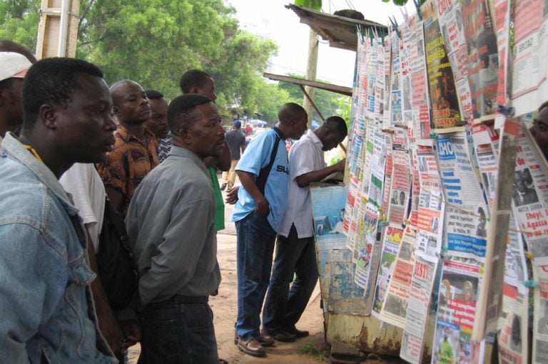 Men gathered at a newspaper stand to read the news, in Lomé, Togo, 4 June 2007, EMILE KOUTON/AFP via Getty Images